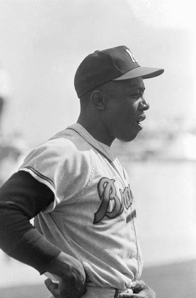 Candid shot of Henry Aaron, as a Milwaukee Brave, standing in uniform with his hands on his hips.