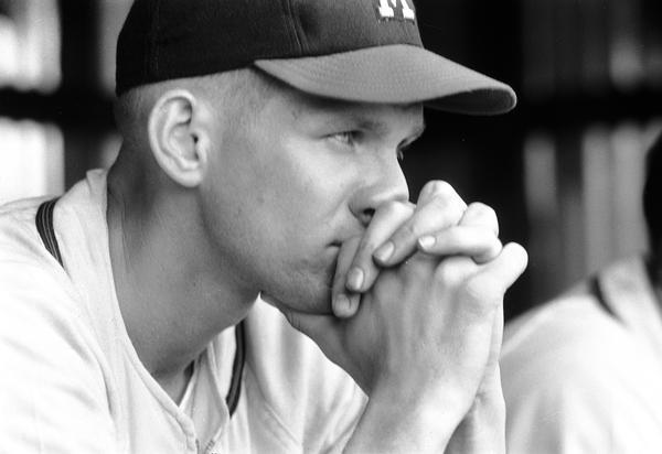 Close-up view of a Milwaukee Braves baseball player resting his chin on his folded hands.