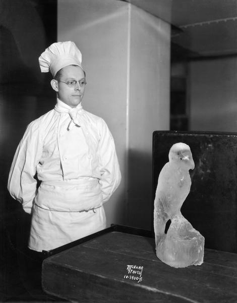 Ottoman Parrhysius, cold meat cook at the Loraine Hotel, posing with a parrot ice sculpture that he created.