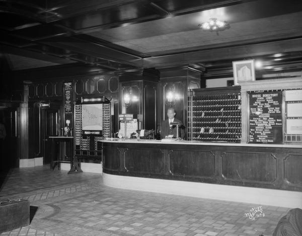 Hotel Loraine lobby from the right with registration desk, desk clerk, local business directory, typewriter and Western Union sign.