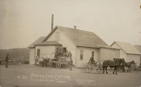 Exterior of the Prairie Farm Creamery with horse-drawn wagons in front. Caption reads: "Prairie Farm Creamery, Pr. Farm, Wis."