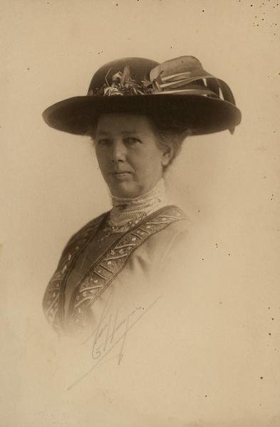 Studio portrait of Clara Bewick Colby wearing large hat.