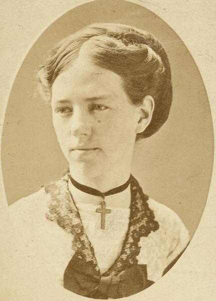 Studio portrait of young Clara Bewick Colby wearing a cross necklace.