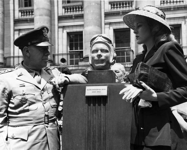 Marge Bong and General Kenney standing by a bust of Major Richard Ira Bong (1920-1945), at the Richard Bong Memorial dedication on Memorial Day.