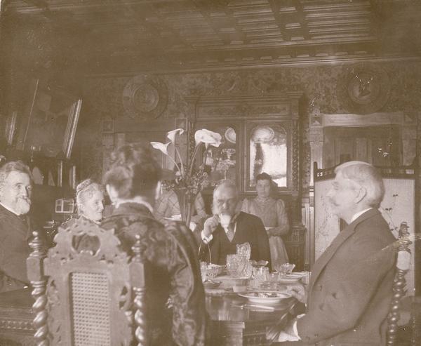 Lucius Fairchild in his dining room with guests, one of which is GAR Commander-in-chief, General Bryant.  Fairchild, a Republican, was the 10th governor of Wisconsin from 1866-1872. Several household staff members appear to be standing in the background.