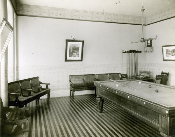 A game room with chairs, a pool table, a rack for cue sticks, and a table with checker board and deck of cards is available for patients' recreation at the Wisconsin State Hospital for the Insane (Mendota Mental Health Institute).