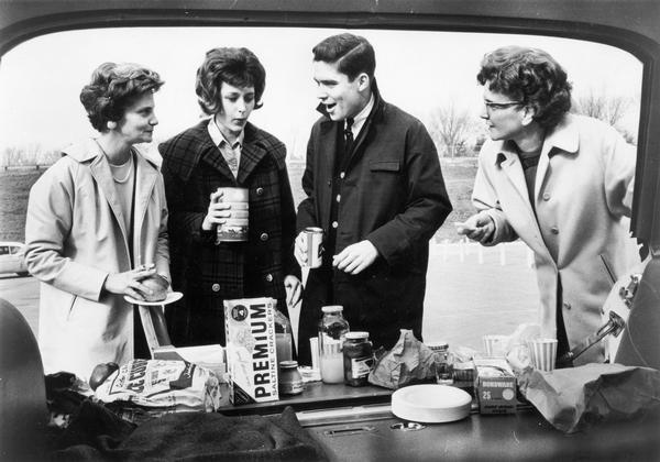 A group of Madison residents, l-r. Mrs. Arthur Freeman, JoAnn Brandt, Scott Freeman, and Mrs. Mary Engler set up their own "refreshment headquarters" on the tailgate of their car preceding the Green Bay Packers game at County Stadium.