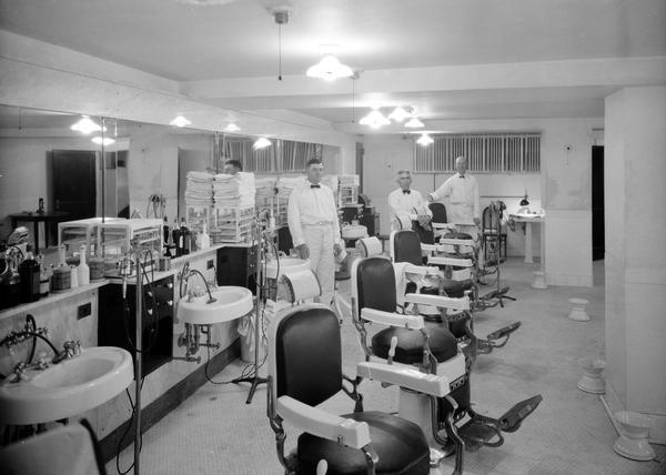 Three barbers stand in the barber shop at the Princess Martha Hotel.