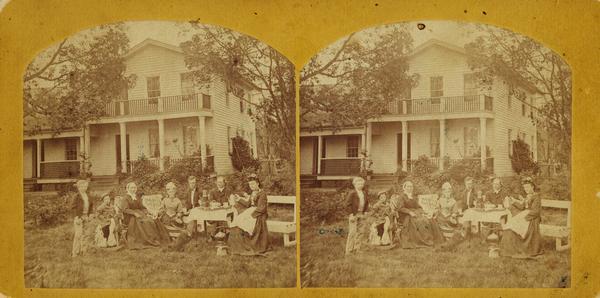Reverend H.A. Preus and his family pose seated outdoors in front of the Spring Prairie parsonage.