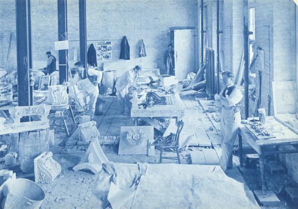 View of construction workers and stone carvers/cutters (some of them probably Italian) showing the detailed sections of the building of the State Historical Society of Wisconsin.