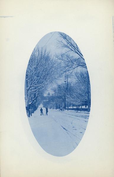 Winter scene of two men standing on a snowy street with the Wisconsin State Capitol visible in the background. They are holding snow shovels.