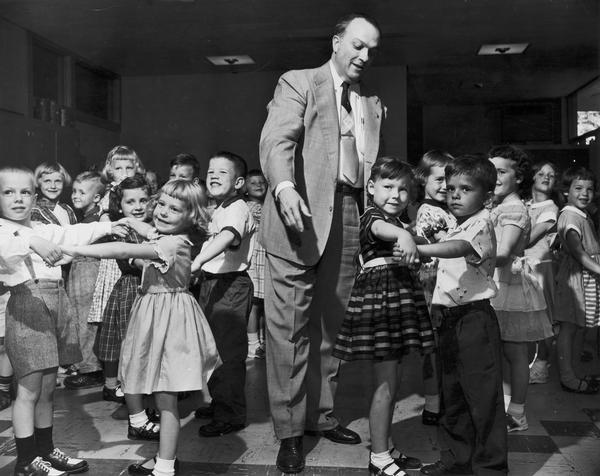 Young children practice ballroom dancing, under the direction of Leo T. Kehl. In addition to the students of the Kehl School of Dance, Kehl also taught boys and girls to dance in many local schools.  The young couple on the left is Gary Morgan and Jo Ann Beso, and on the right, Paula Gronet and Dennis Wireg.