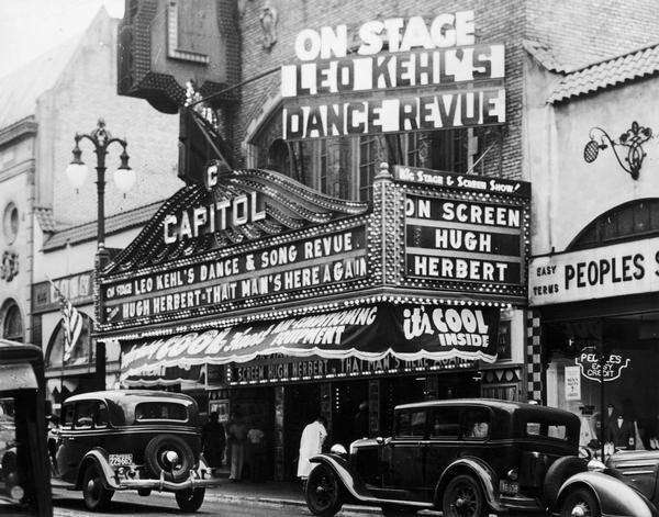 The Capitol Theatre marquee advertising a dance and song revue on stage by the Kehl School of Dance, under the direction of Leo Kehl and "That Man's Here Again," with Hugh Herbert on screen.  The image shows some State Street automobile traffic.