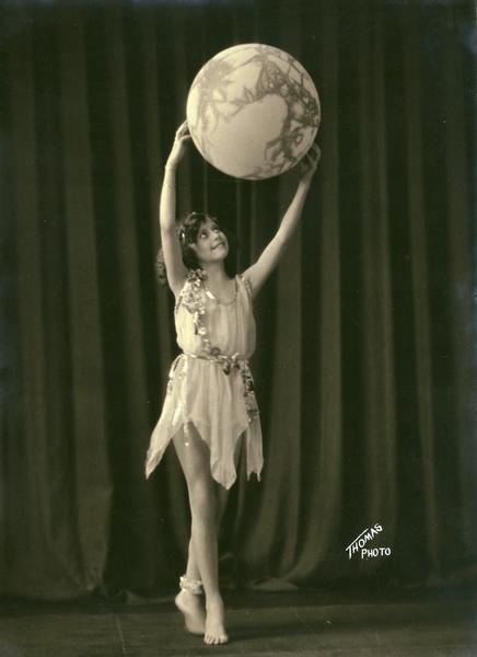 A young barefoot dancer from the Kehl School of Dance in Madison posed with a large globe.  Props were often included in dance numbers choreographed by Leo Kehl and his father F. W. Kehl.