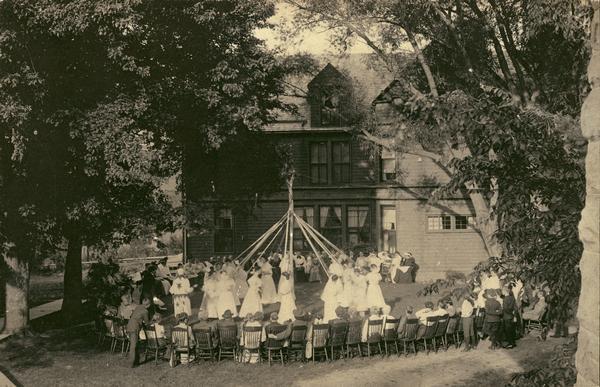 Elevated view of students at the Hillside Home School performing a may pole dance while an audience looks on. Dance instruction at the school was provided by Frederick W. Kehl (1862-1938) of the Kehl School in Madison. Kehl traveled to the school every other Friday evening to teach the students ballroom dancing and conduct other special entertainments. The Hillside Home School was operated by Jane and Ellen Lloyd Jones, aunts of Frank Lloyd Wright.