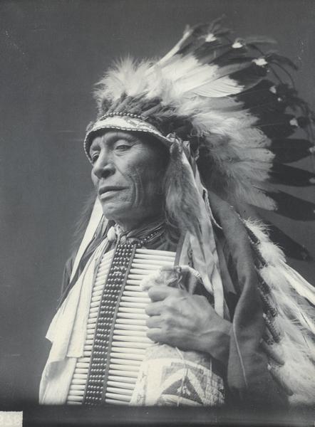 Studio portrait of Canmonpatoankantuya, also known as James High Pipe, holding a bag. Part of the Siouan (Sioux) and Brule Tribes.