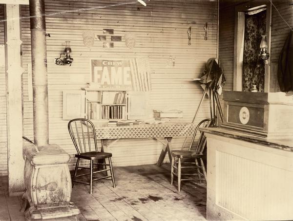 Interior view of traveling library station including a sign that reads "Chew Fame" and a wood burning stove.