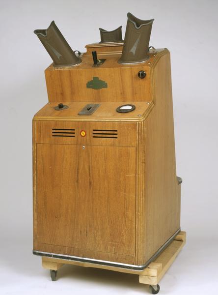 The shoe fitting fluoroscope was a common fixture in shoe stores during the 1930s, 1940s and 1950s. A typical unit, like the machine shown here, consisted of a vertical wooden cabinet with an opening near the bottom into which the feet were placed. When you looked through one of the three viewing ports on the top of the cabinet (e.g., one for the child being fitted, one for the child's parent, and the third for the shoe salesman or saleswoman), you would see a fluorescent image of the bones of the feet and the outline of the shoes.