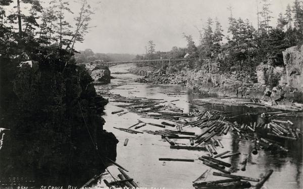Elevated view of a log jam near the Dalles on the St. Croix River. Caption at bottom reads: "St. Croix Riv. and Bridge, St. Croix Falls."