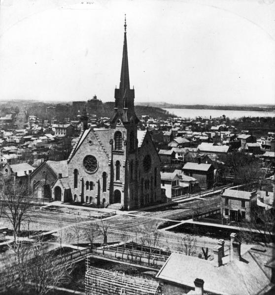 Elevated view of the First Congregational Church and chapel at the corner of North Fairchild Street and West Washington Avenue. The Gates of Heaven Synagogue is on the left, also on West Washington Avenue. In the distance are University Avenue, Bascom Hall and Lake Mendota.