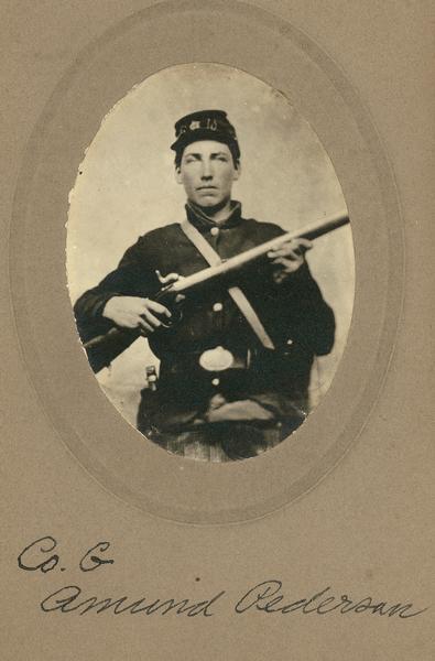 A waist-up studio portrait of Amund Pederson, a private in Company G, 15th Wisconsin Infantry in uniform holding a musket across his chest.  The following information was obtained from the Regimental and Descriptive Rolls, Volume 20:  he resided in Martell, Wisconsin. On November 11, 1861, he enlisted in Martell, Wisconsin and was mustered into service in Madison, Wisconsin on December 13, 1861.  The muster rolls also state that he served as a guard on a supply train to Stevenson, Alabama in October 1863. He was mustered out with Company G on January 13, 1865 in Chattanooga, Tennessee..