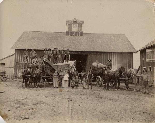 Threshing on the Henry Johnson farm. This threshing rig owned by Michael Ehlinger was the first to be used in the township. Standing on the separator from left to right: John Hoeffs, Ernest Schuettpelz, George Smith, Max Schuettpelz, unidentified man, and Paul Schuettpelz. Seated are Michael Ehlinger and Fred Luebuck. On the ground: Betha Dieck, unidentified man, Mrs. Henry Johnson (Augusta Dierck), holding baby Gladys (born May 1896), L.C. Harvey (in suit), Harvey Armstrong behind the twins Lillian and Leonard Johnson, John Overlough, Michael Ehlinger Sr., seated on the steam engine, and Ed Finley holding the team. Henry Johnson is holding his son Millard's hand.