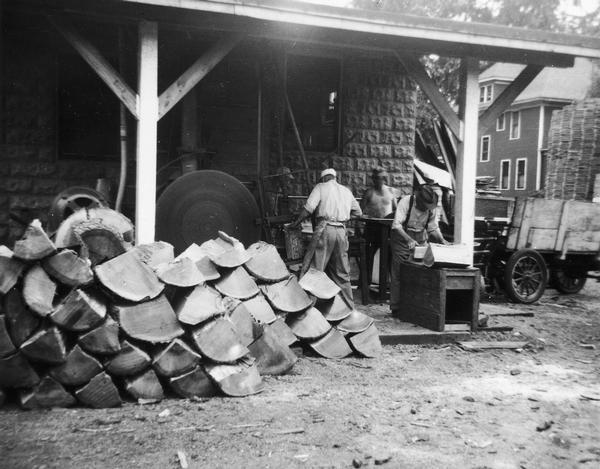 Three employees working at the Hess Cooperage sawmill, quarter sawing oak logs to make staves and heads for barrels.