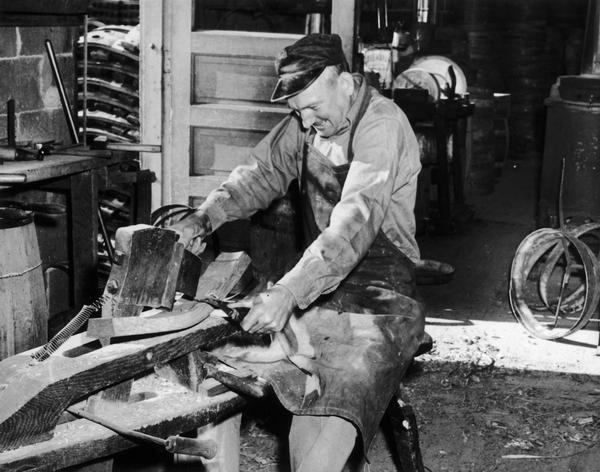 Frank "Foots" Hess Jr. using a draw knife to shape an oak barrel stave at the Hess Cooperage. Also known as "schnitzeling on the schnitzelbank".