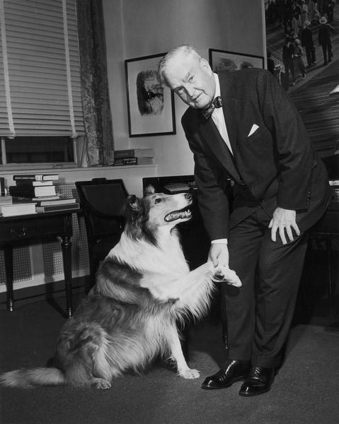 Bruce Barton shakes hands (paws?) with Lassie, famous canine television performer.
