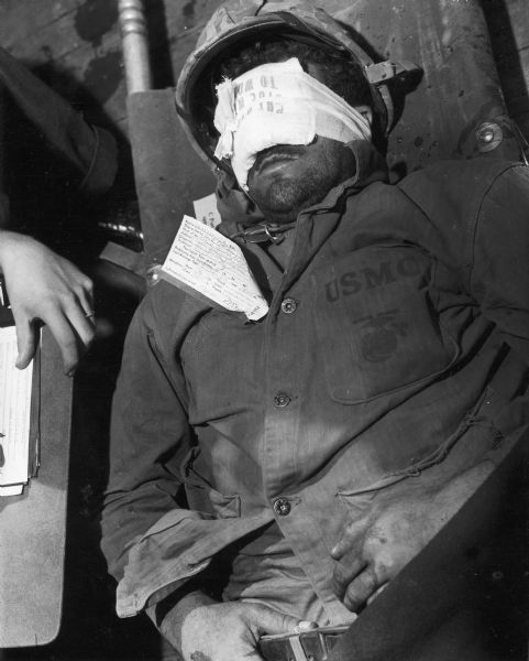 A marine from the USS "Samaritan" lays on a stretcher with his eyes bandaged.