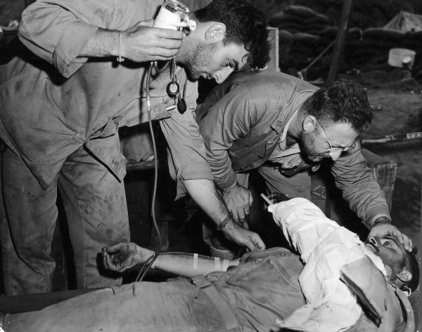 Two doctors attend to a wounded man on a stretcher in Iwo Jima.
