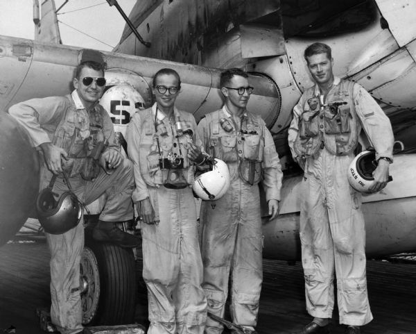 Dickey Chapelle posing in flight suit with three pilots including crew members Weston and Gillen.