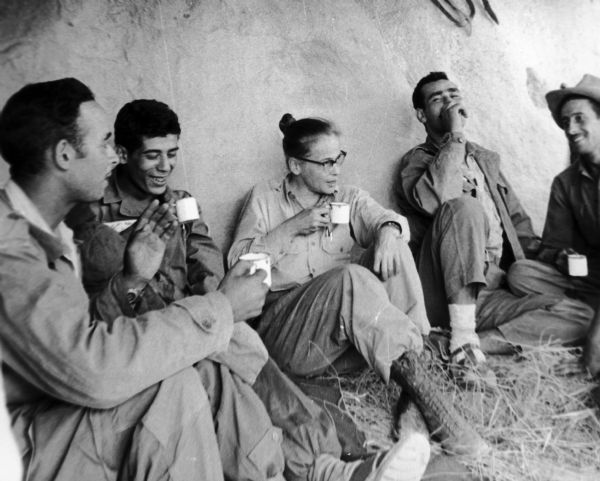 Dickey Chapelle sitting with the FLN Scorpion Battalion Rebels in the Atlas Mountains in Algeria drinking tea.