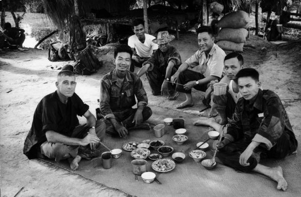 United States advisor Captain Jeffers has a meal with six Vietnamese men.