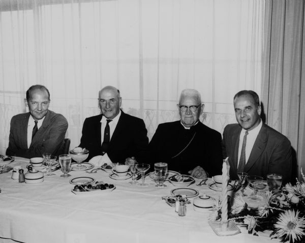 From left to right, Ivan A. Nestigen, Dr. Tomey, Bishop O'Conner, and Governor Gaylord Nelson at a dinner table.