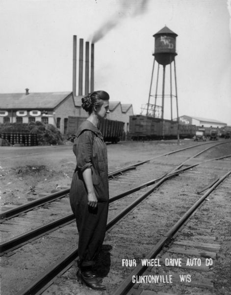 A woman stands in front of the Four Wheel Drive Auto Company factory in Clintonville.