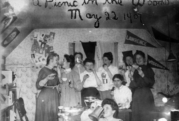 A group of girls eating and drinking in a college dormitory (?). The title "A Picnic In The Woods" was scratched into the emulsion of the original glass plate.