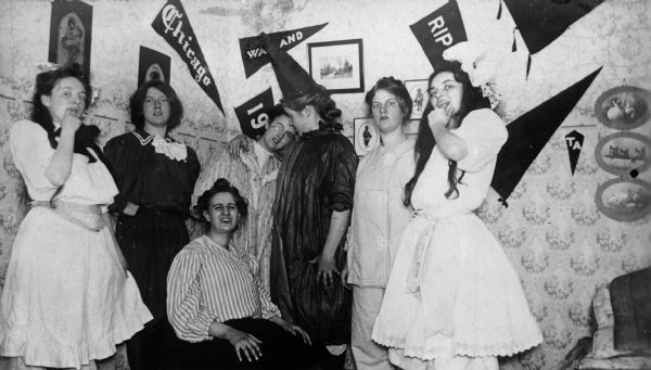 Group of women clowning around in dorm room with pennants on the wall.