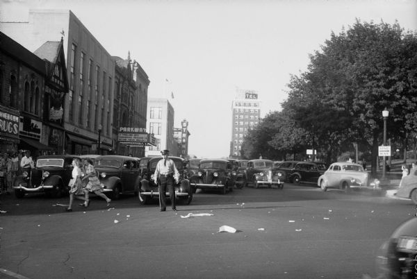 Automobiles and police officer on West Mifflin Street. Celebration of V-J Day August 15, 1945, the day on which the Allies announced the surrender of Japanese forces during World War II.
