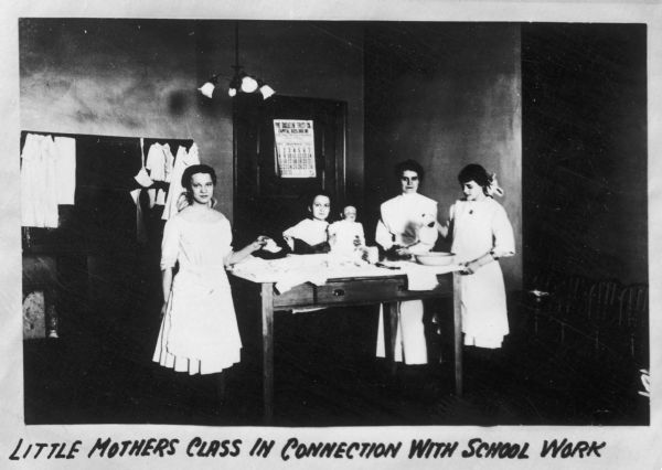 Mothers in class learning to care for their babies. The caption reads: "Little Mothers Class in Connection with School Work".