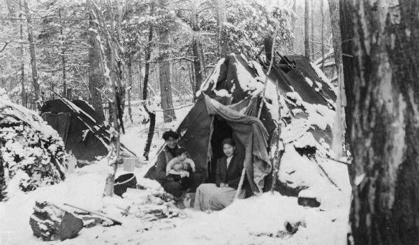 Vicinity of the New Dells Lumber Company logging camp. Chippewa family on a snowy day at their camp site.