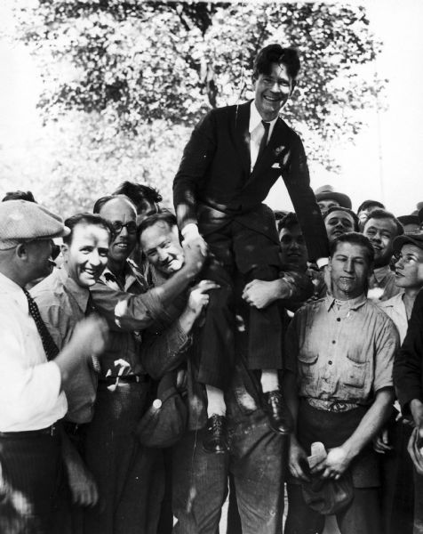 Philip La Follette sits on the shoulders of a man in a crowd of supporters, possibly during his 1930 campaign for the governorship of Wisconsin.
