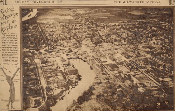Aerial view of town with river. The clipping from a newspaper has a description titled: "Seeing Wisconsin From an Airplane".