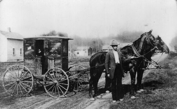 Mail wagon, circa, 1889. Man in photograph: Ralph Jones. Wagon given to the Wisconsin Historical Society (Cassville), by Mr. Jones, who also presented the original hand-colored photograph.