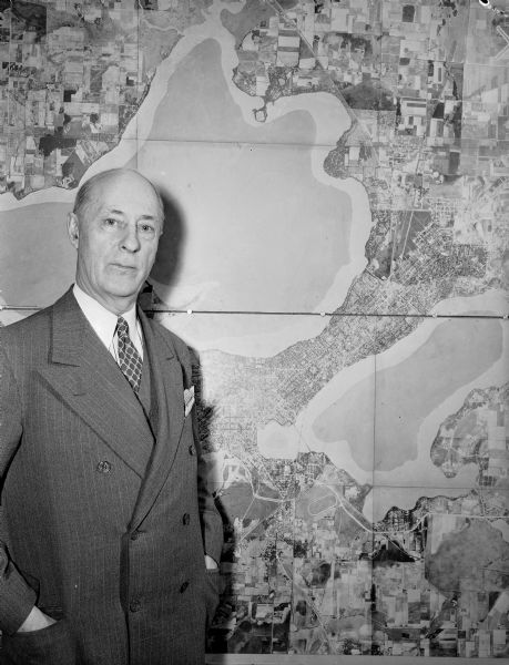 Joseph W. Jackson (Col. Bud), executive director of the Madison and Wisconsin Foundation, standing next to a map of the isthmus.