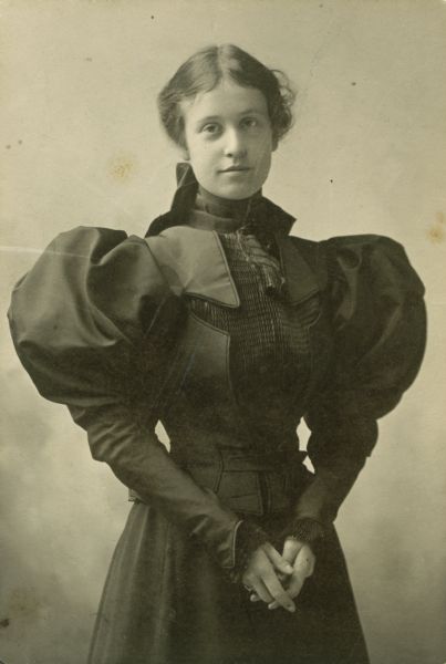 Portrait of Caryl Fairchild (later Caryl Fairchild Bacon), youngest daughter of former governor and Civil War hero Lucius Fairchild.  This photograph is dated "Christmas 1896."  Because her father had died only six months earlier, the color of Caryl's dress with its enormous puffed sleeves is a sign that she was still in mourning.