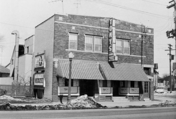 Exterior front view of Tony Urso's Westside Palm Tavern located at 730-736 West Washington Avenue in the Greenbush neighborhood. Typewritten sheet with photograph reads: "This is a very well built building with a large dining room and bar on first floor with a restaurant kitchen in the same building since 1912. Building has been remodeled several times and is in good condition, has recently been equipped with new aluminum combination screens and storms."