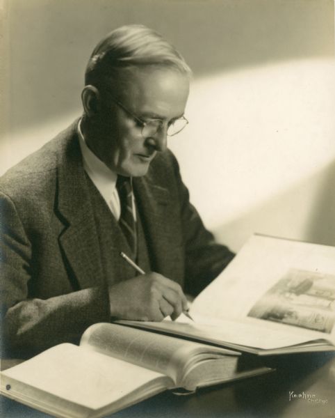 Studio portrait of Chester Thordarson seated with books and a pencil.