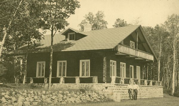 Exterior view of a lodge, probably on Rock Island in Door County. Two men pose in front of the building.