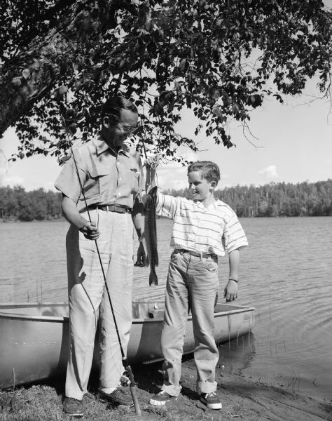 Edward R. Murrow, with a young boy (possibly his son Casey), displaying a Northern Pike they caught while fishing on a lake in northern Wisconsin.